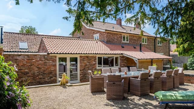 Spacious outdoor seating area with wicker chairs, a stone path, and a brick building under a clear blue sky.