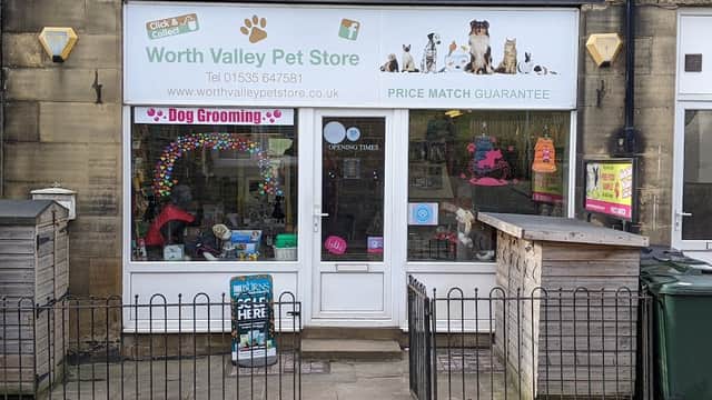 Pet shop storefront featuring colorful signage, dog grooming service, and a fenced entrance in Haworth, Yorkshire.