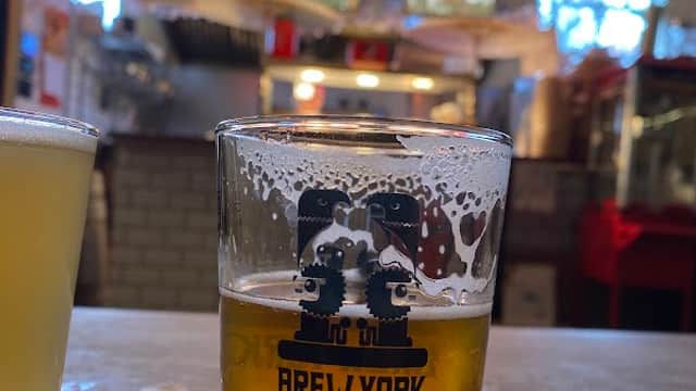 Brew York glass of beer on a wooden flight, with vibrant red lanterns and colorful banners in the background.