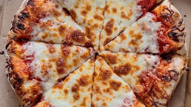 A freshly baked cheese pizza, sliced into eight pieces, in a cardboard pizza box.