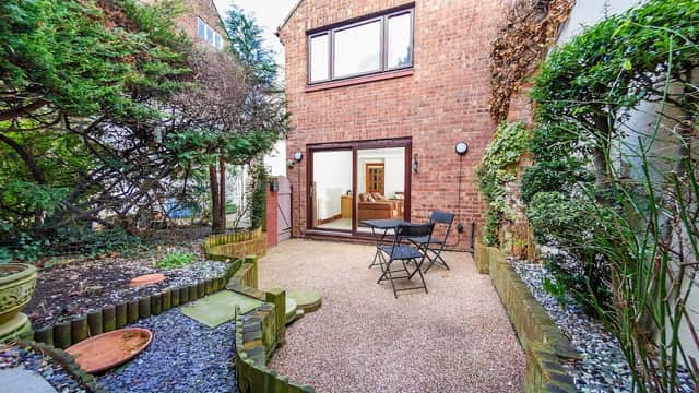Cozy courtyard with gravel, potted plants, and a small table set for two, leading to a hotel interior in Whitby.
