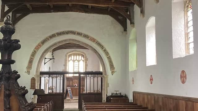 Interior of St Mary's Church featuring wooden beams, pews, and stained glass windows.