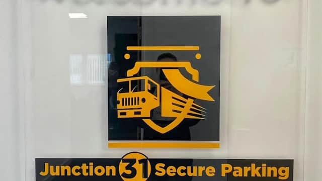 Welcome sign for Junction 31 Secure Parking, featuring a truck graphic and text highlighting commercial vehicle parking.