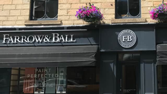 Farrow & Ball showroom in Harrogate with stone facade, large windows, and colorful flower baskets.