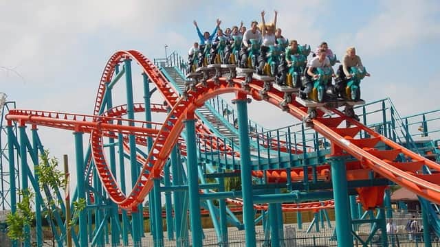 Roller coaster "Velocity" with riders in excitement, twisting tracks, and vibrant blue and red colors in Kirby Misperton.