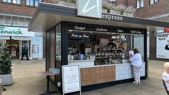 Modern food kiosk with a sign reading "21 express," offering breakfast, sandwiches, and pastries in a shopping area.