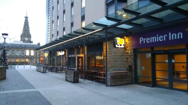 Broad Street Plaza features outdoor seating, modern architecture, and the Premier Inn sign, with a church tower in the background.