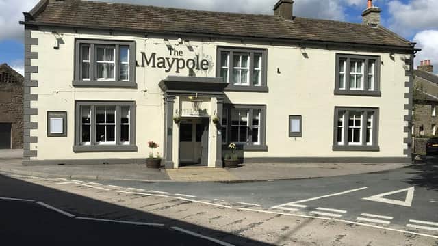 The Maypole Inn, a charming pub with a white and grey facade, situated at a street corner in Long Preston, Yorkshire.