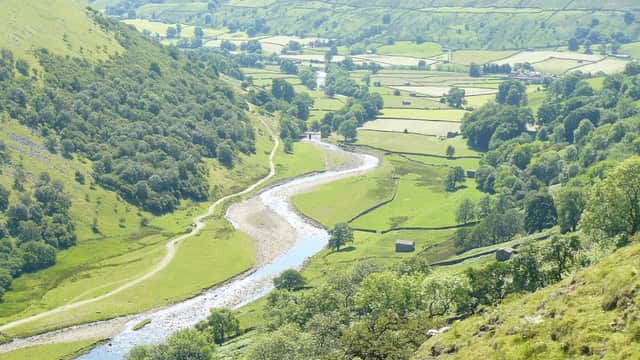 Scenic view of rolling green hills, a winding river, and lush farmland in Thwaite, North Yorkshire.