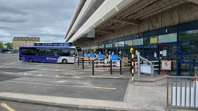Pay & Display car park at Huddersfield Bus Station with buses, signage, and parking barriers under a cloudy sky.