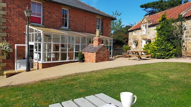Charming boutique hotel with a red brick exterior, outdoor seating, and a sunny garden area in Hinderwell, Yorkshire.