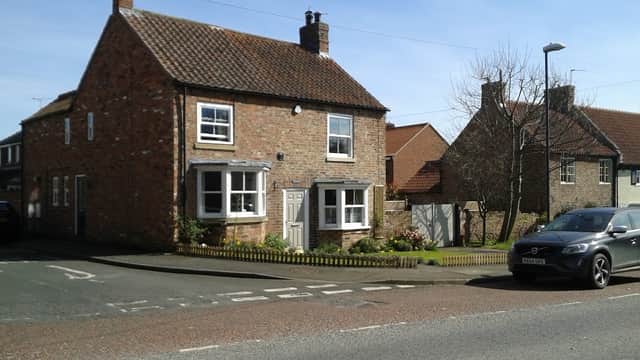 Topcliffe Village Hall, a brick building with a pitched roof, surrounded by greenery and residential homes.