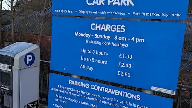 Welcome sign for Bridge Lane Car Park with parking charges and payment machine visible in Holme Valley, Yorkshire.