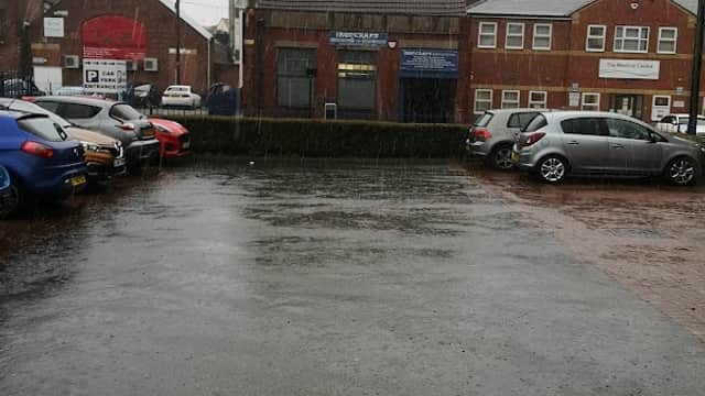 Pay & Display car park in Doncaster, wet pavement, parked cars, buildings in the background, overcast sky.