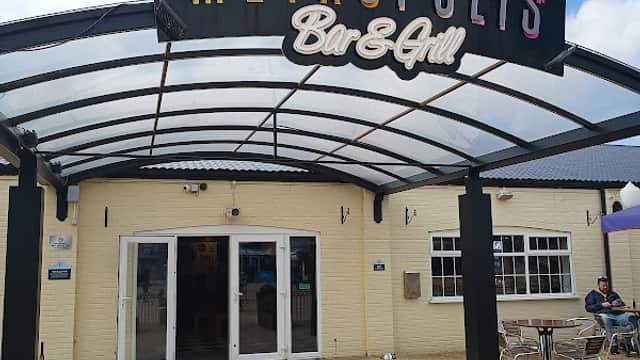 Entrance to Metropolis Bar & Grill featuring a colorful skyline sign and outdoor seating area in Kirby Misperton.