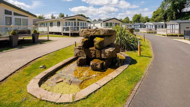A landscaped holiday park featuring a stone fountain, neatly arranged homes, and a sunny sky in Yorkshire.