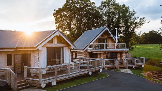 Two wooden cabins with balconies, surrounded by greenery, under a sunset sky at Olicana Park, Addingham, Yorkshire.