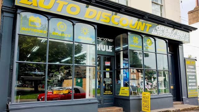 Bike shop storefront with large "AUTO DISCOUNT" sign, displaying services like batteries and brakes, in Harrogate.
