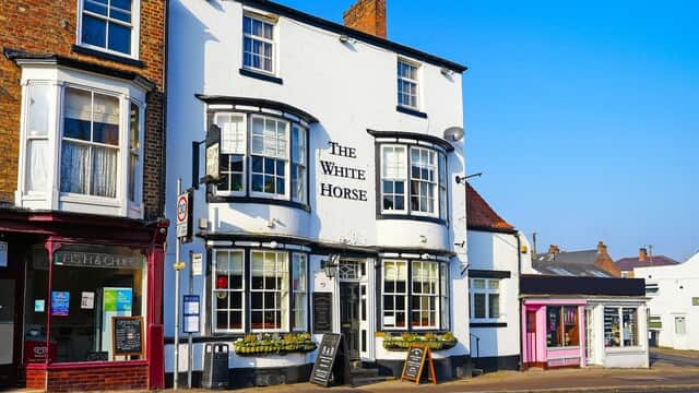 The White Horse guest house features a white exterior, large windows, and a welcoming entrance in a quaint Yorkshire street.