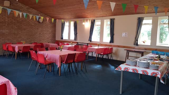 Brightly decorated hall with red checkered tables, colorful bunting, and floral centerpieces.