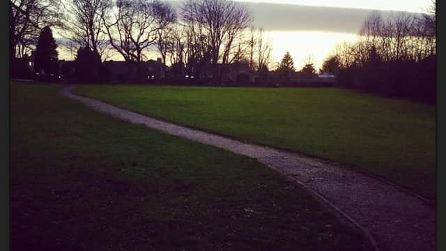 Path winding through a grassy field, surrounded by trees under a twilight sky in Collingham, Yorkshire.