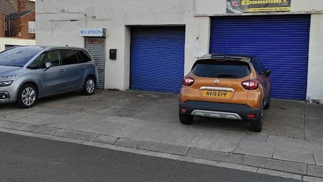 Fishermans Square Garage with blue doors, signage, and parked cars in front on a street in Redcar, Yorkshire.