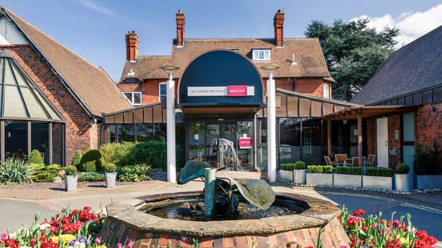Elegant brick facade of Mercure Royal Hotel with a fountain and vibrant flower beds in the foreground.