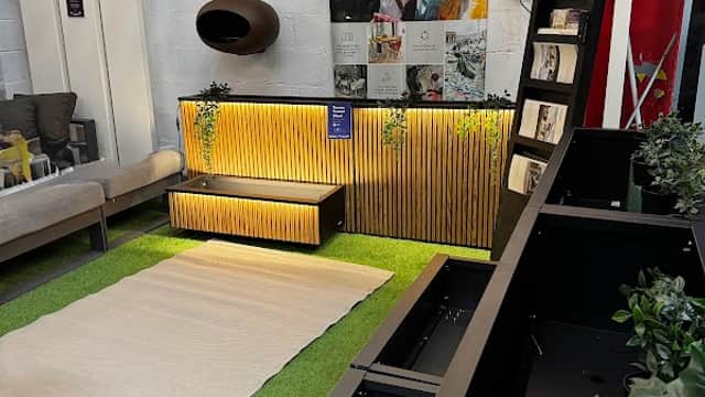 Modern showroom featuring stylish furniture, greenery, and a display with a wooden accent wall.