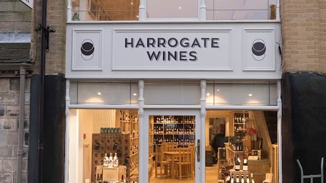 Exterior of Harrogate Wines with large windows, wooden display cases, and a sign featuring the name prominently.