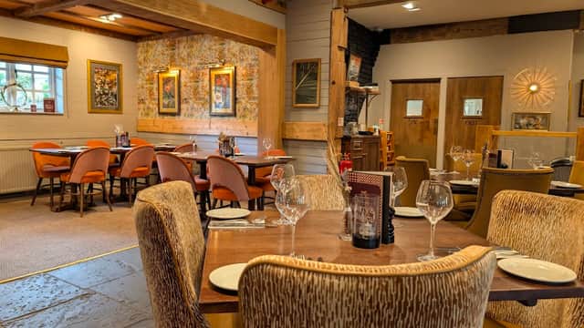 Cozy restaurant interior with wooden beams, elegant tables set with glassware, and warm lighting in Mosborough, Yorkshire.