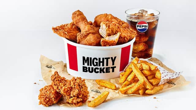 Mighty Bucket filled with fried chicken, fries, and a glass of Pepsi on a white background.