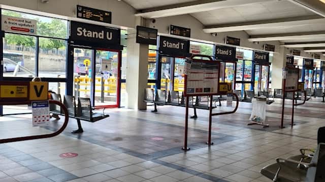 Interior of Huddersfield Bus Station featuring multiple bus stands and waiting areas with clear signage.