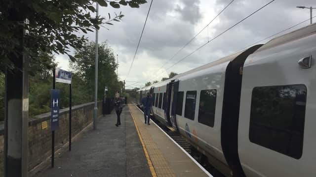 Bus stop at South Elmsall with passengers waiting and a train arriving, under a cloudy sky.