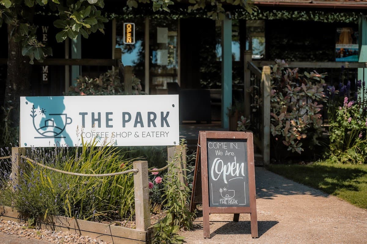 Sign for The Park Coffee Shop & Eatery, with a welcoming entrance and lush greenery in Wykeham, Yorkshire.