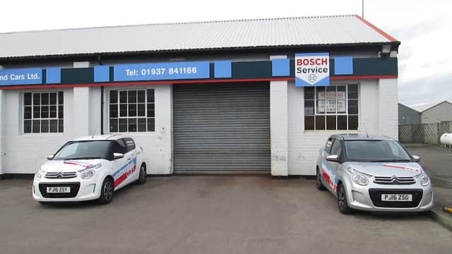 Westmoreland Cars Ltd shopfront with two cars parked outside, featuring Bosch Service signage and a shuttered entrance.