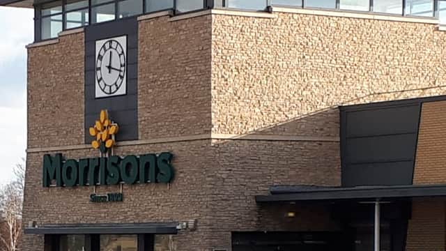 Morrisons store in Knottingley, Yorkshire, featuring a stone facade and a clock tower, with cars parked outside.
