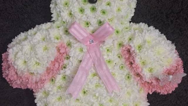 Floral teddy bear arrangement made of white and pink flowers, featuring black button eyes and a pink ribbon bow.
