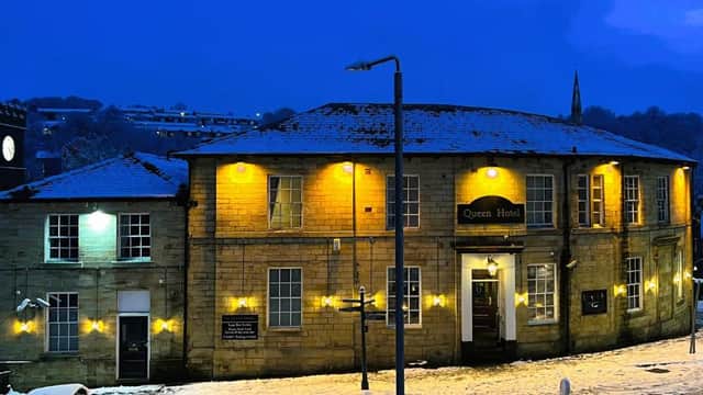 Historic stone hotel with warm lights, snow-dusted roof, and surrounding winter landscape at dusk.