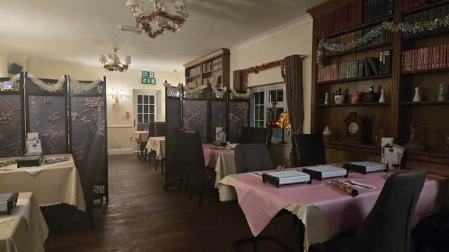 Cozy dining area with pink tablecloths, wooden bookshelves, and decorative screens in a warm, inviting atmosphere.