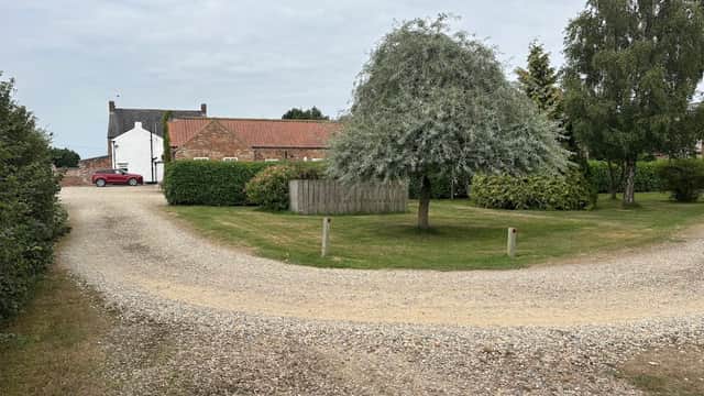 Old Oak Cottages in Thirkleby, Yorkshire, featuring a gravel driveway, lush greenery, and a large tree.