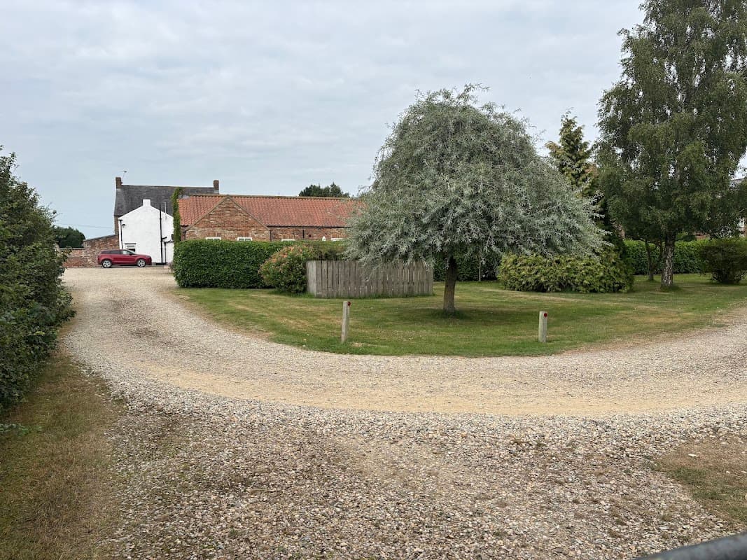 Old Oak Cottages in Thirkleby, Yorkshire, featuring a gravel driveway, lush greenery, and a large tree.