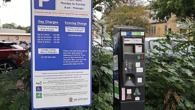 Bingley Arts Centre car park sign with pay & display machine, surrounded by greenery and parked cars.