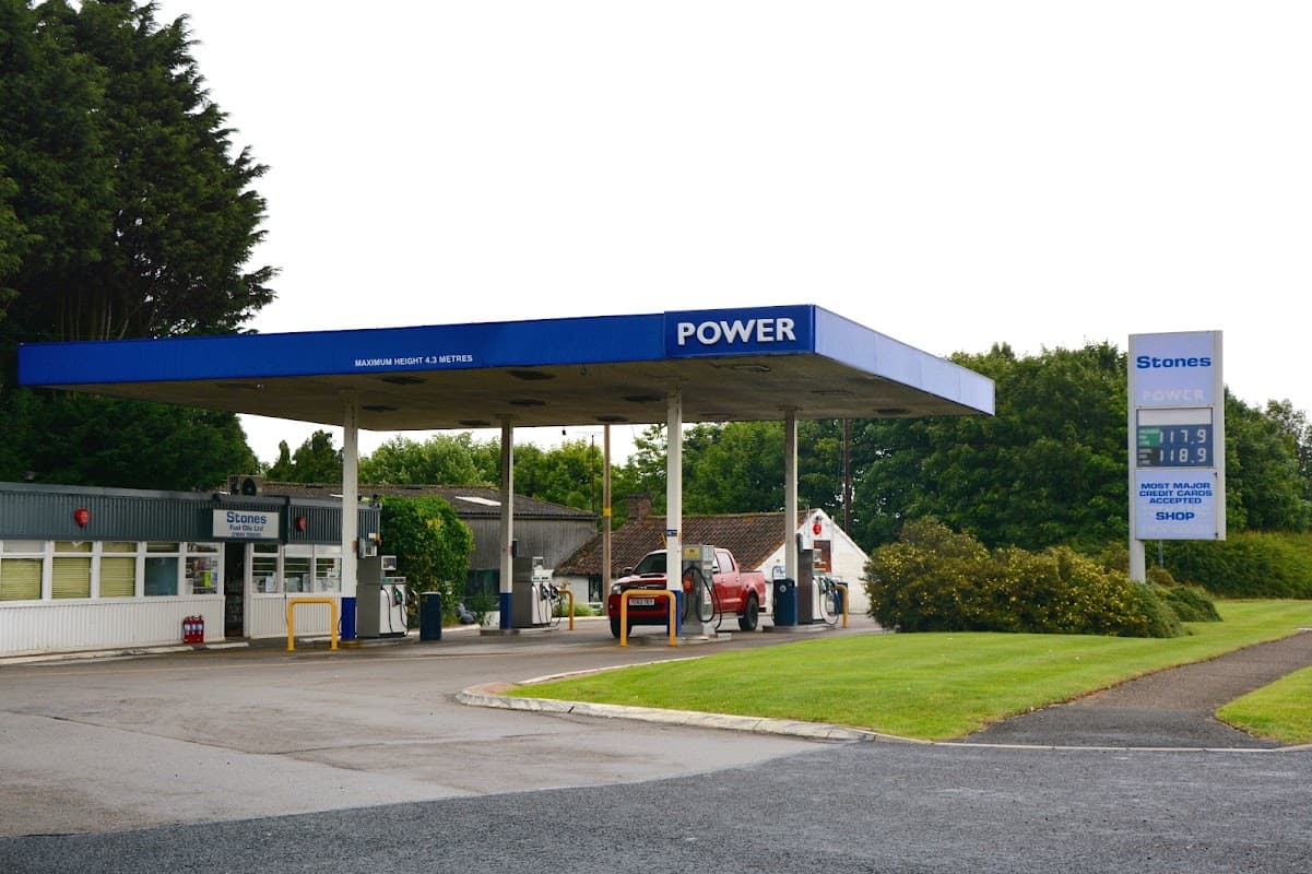 Gas station with "POWER" signage, fuel pumps, and a shop, surrounded by greenery in West Heslerton, Yorkshire.