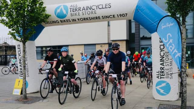 Cyclists begin a ride under a large inflatable arch with "All Terrain Cycles" in Saltaire, Yorkshire.