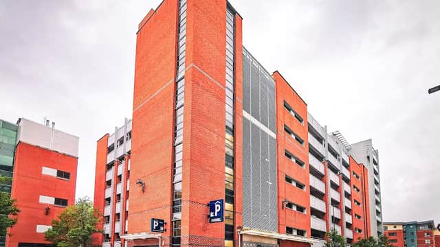 Modern multi-story car park with red brick exterior, large windows, and parking signage in Sheffield, Yorkshire.