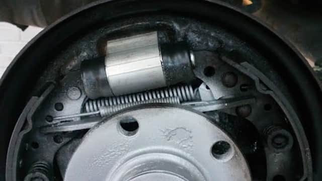 Close-up of a car brake drum assembly showing the brake shoes, spring, and cylinder components.