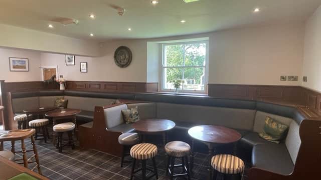 Cozy seating area with wooden tables and chairs, large window, and decorative wall art in a welcoming ambiance.