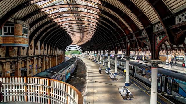 Historic train station with arched glass roof, platforms, and trains, showcasing architectural details and waiting areas.