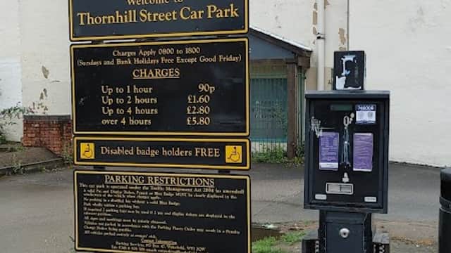 Sign for Thornhill Street Car Park with parking charges, payment machine, and nearby buildings in Wakefield, Yorkshire.