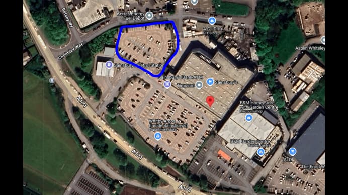 Pay & Display parking area in Whitby, Yorkshire, marked in blue, near shopping facilities and other parked cars.